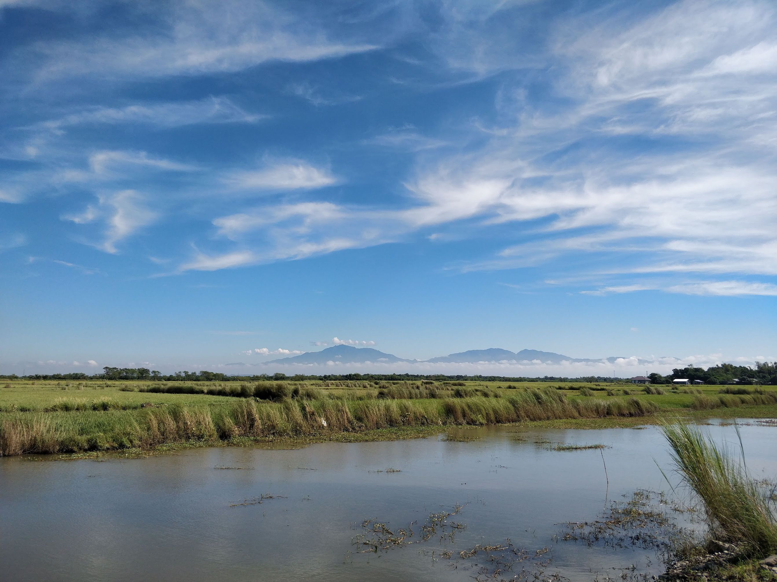 Blue sky and clouds over a mountain range and a pond